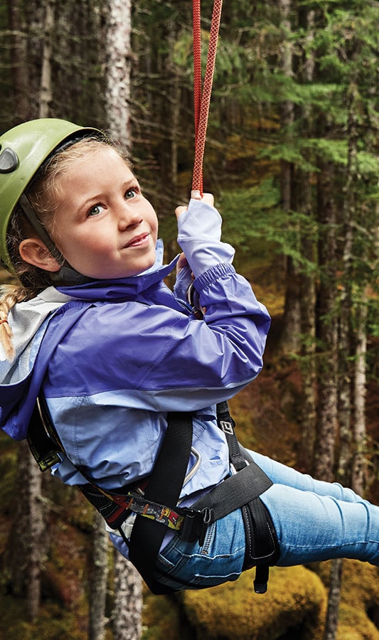 A kid on a zipline while on an Alaska shore excursion